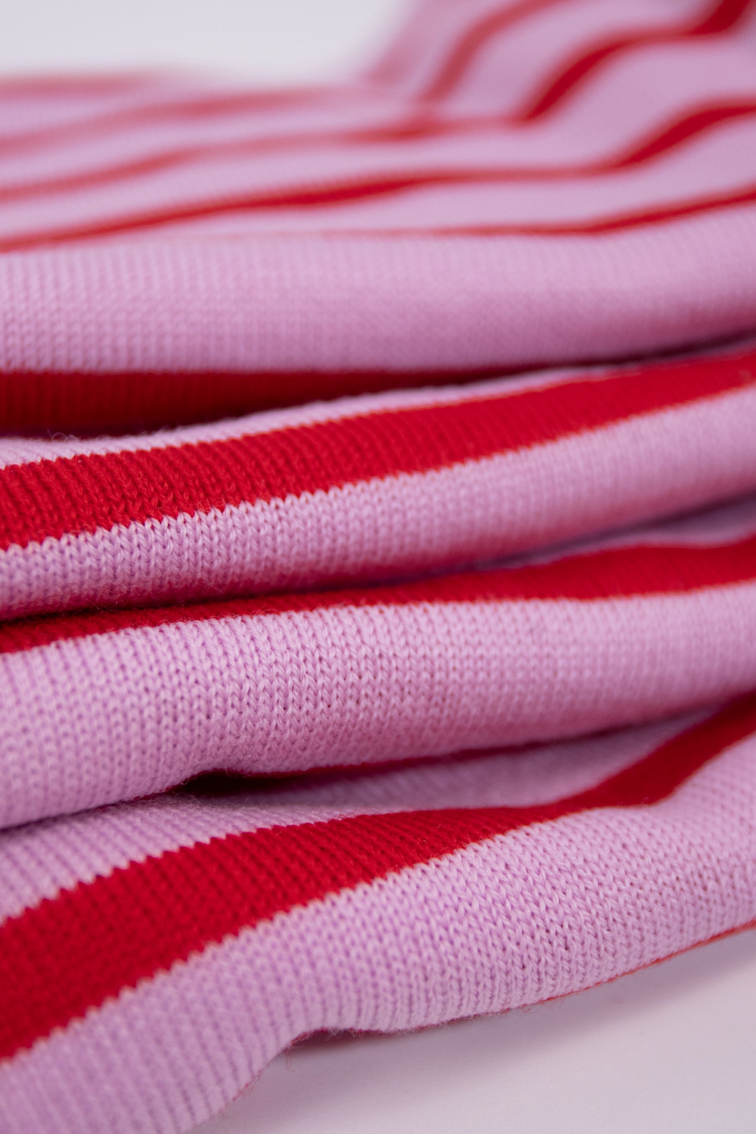 Close-up of the pink and red stripes on the merino wool Marinière, soft and thermo-regulating fabric, ideal for a casual chic look