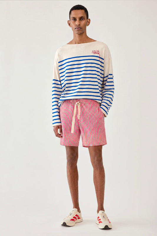 Man wearing a blue and white Breton shirt by Atelier Marinière with red striped shorts, showcasing the relaxed oversized fit, handcrafted in Italy from premium cotton