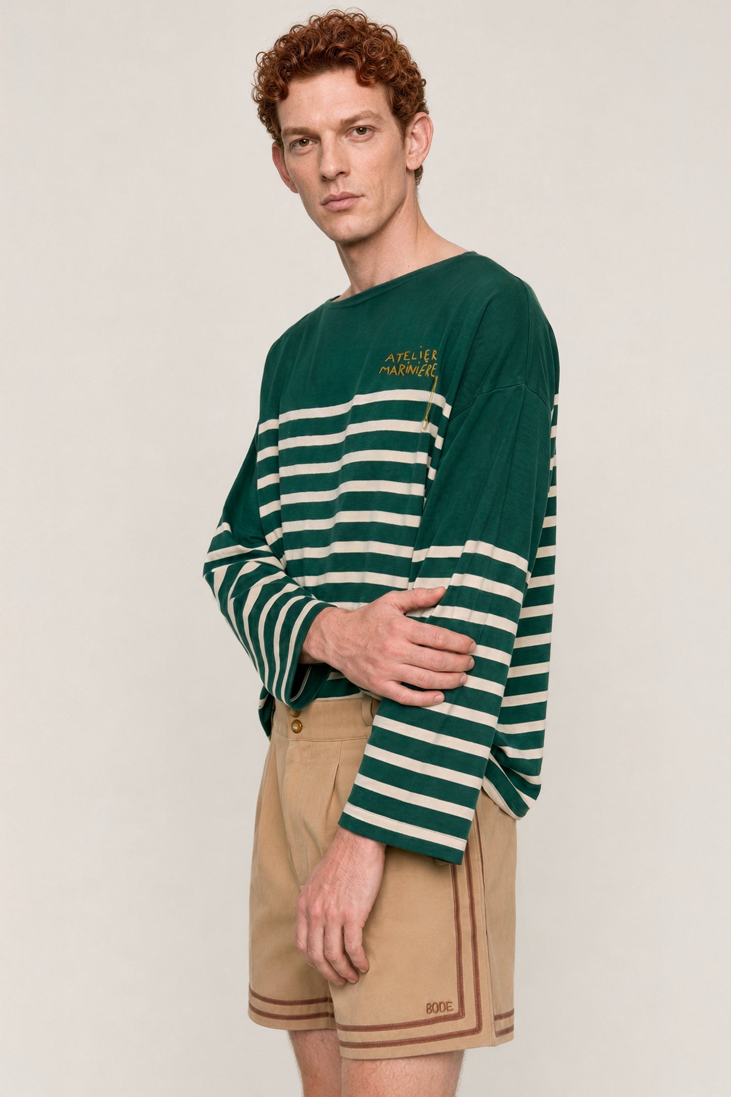Close-up of a men's green and white Breton shirt by Atelier Marinière showcasing the oversized fit, wide boat neck and handcrafted embroidery, handcrafted in Italy from premium cotton